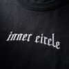 Detailaufnahme der gestickten Wordmark inner circle unterhalb des Kragens