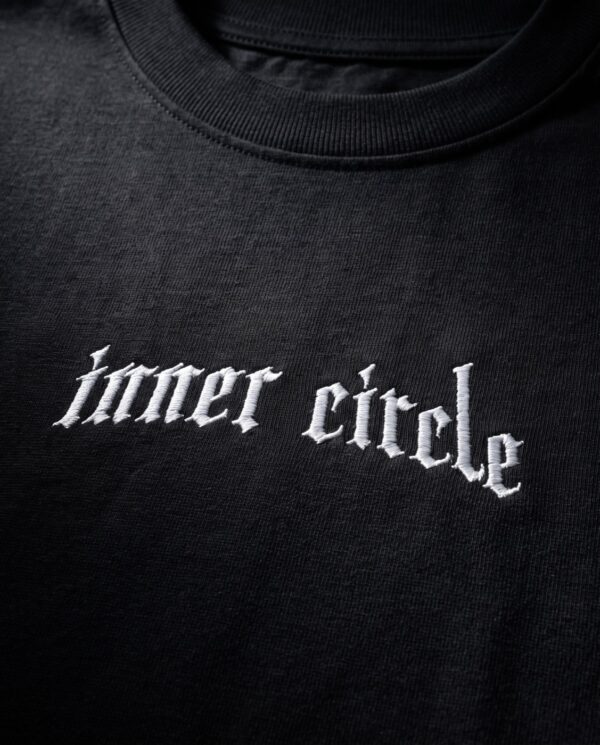 Detailaufnahme der gestickten Wordmark inner circle unterhalb des Kragens